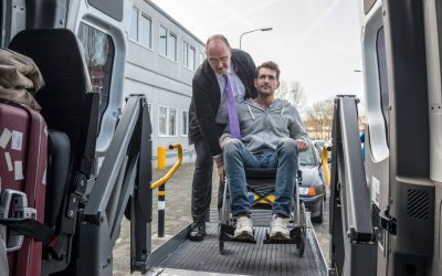 Professional cab driver assisting man on wheelchair to board hydraulic lift van